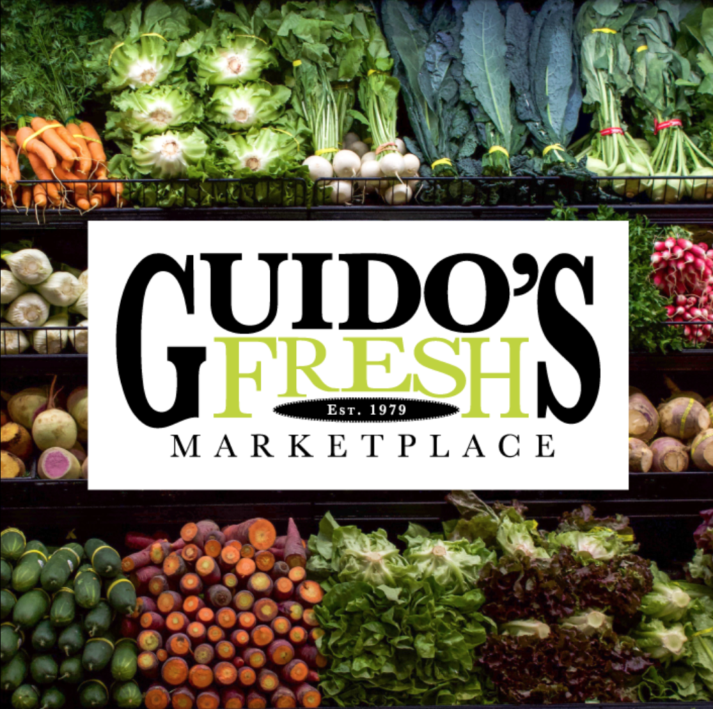Logo of Guido’s Fresh Marketplace, established in 1979, placed over an image of fresh vegetables in a grocery display.